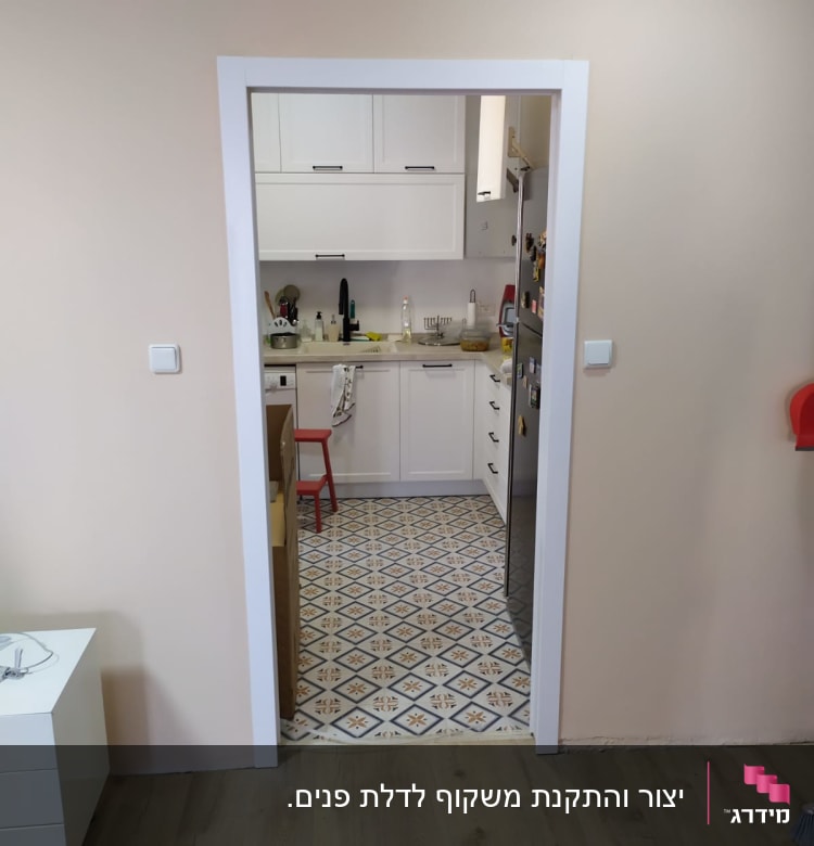 מטבח עם ארונות לבנים ורצפת אריחים מעוצבת